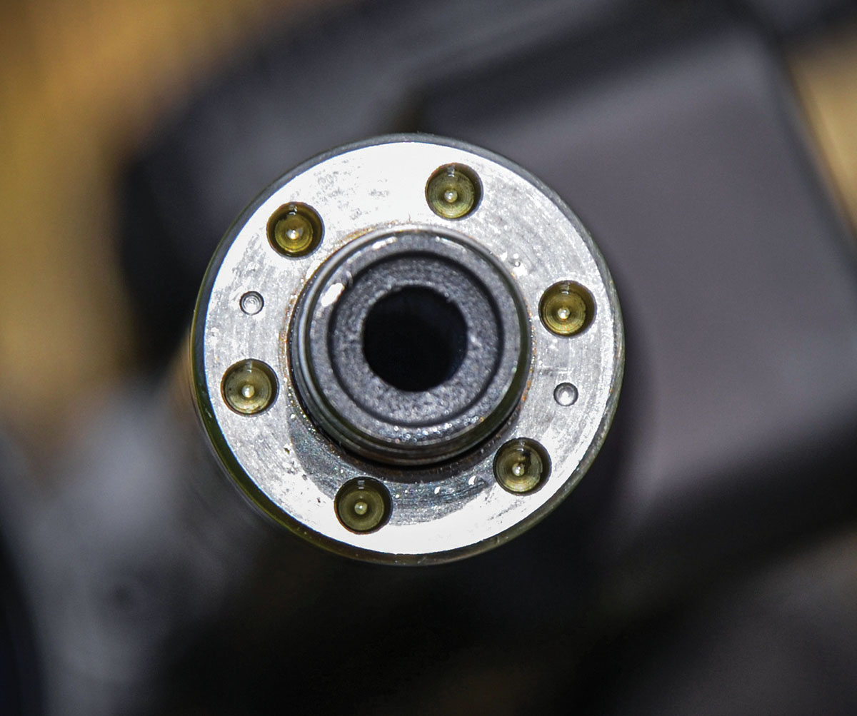 This target’s close-up view shows the muzzle of the 1/2-28 threaded barrel with the barrel tensioning nut attached. When the barrel is assembled at the factory, a spanner wrench is used to turn the nut clockwise, applying force against the front of the carbon fiber tube - which fits loosely around the thin stainless steel - with its opposite end resting against a shoulder machined into the barrel at the receiver. This stretching or tensioning force on the barrel uniforms and dampens harmonic vibration. Not seen here, the threaded shank extends .380 inch beyond the tensioning nut for attachment of a muzzle brake or suppressor.